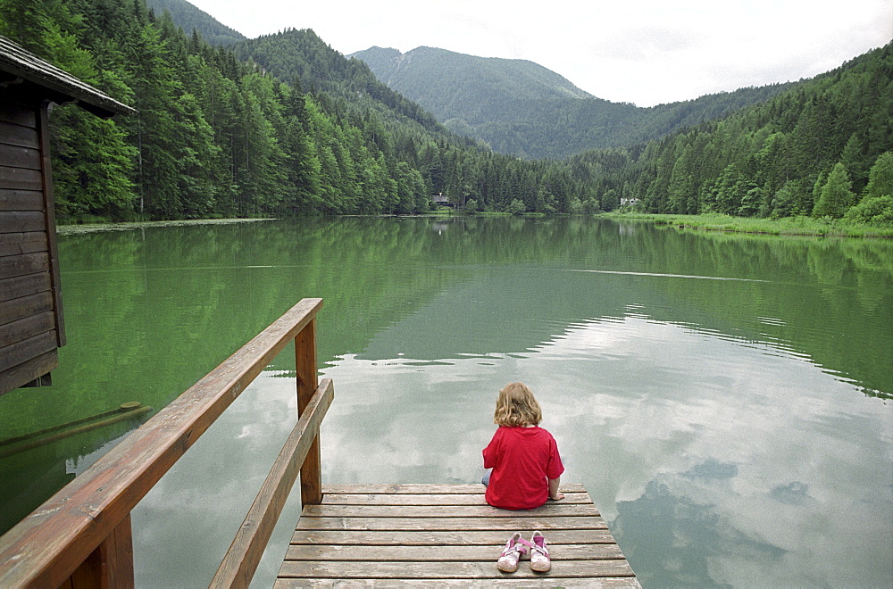 A little girl sitting by a lake, Schaffner Weiher, Stodertal, Austria, Alps, Europe