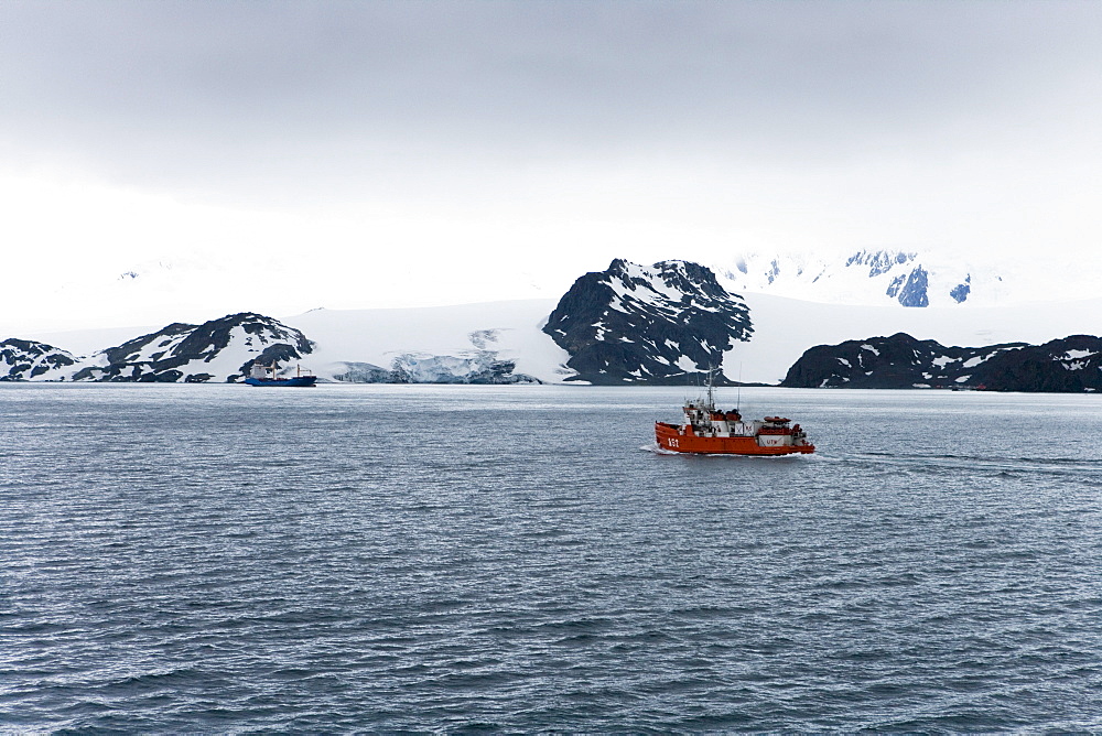 Expedition boat and glacier under clouded sky, False Bay, Livingstone Island, South Shetland Islands, Antarctica