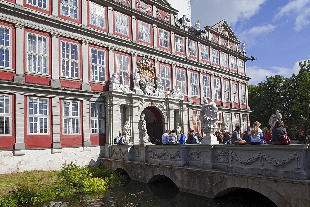 Entrance to Wolfenbuettel castle, now a secondary school, pupils sitting on the bridge, Wolfenbuettel, Lower Saxony, Germany