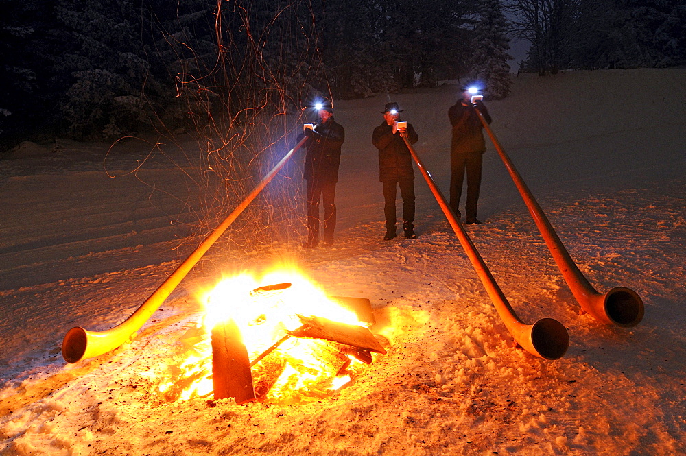 Alphorn players at a bonfire in the snow, Hemmersuppenalm, Reit im Winkl, Chiemgau, Upper Bavaria, Bavaria, Germany, Europe