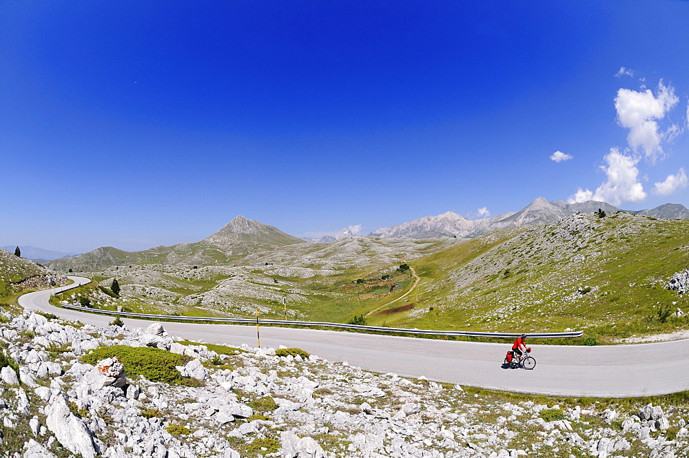 Cyclist on lonesome country road, Castel del Monte, Campo Imperatore, Abruzzi, Italy, Europe