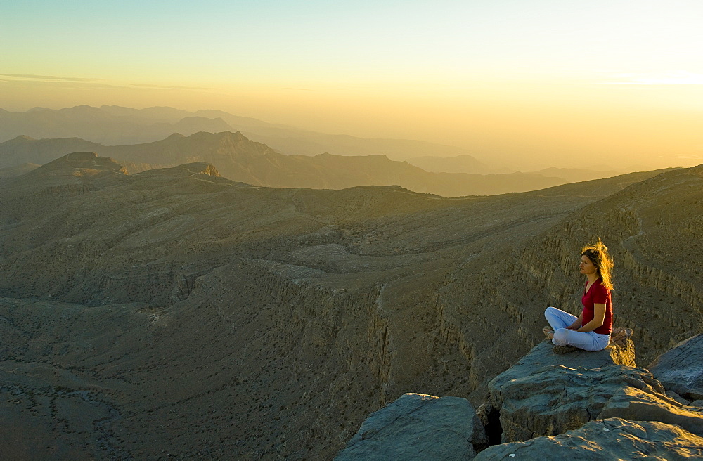 Woman sitting on the edge of a rock watching the sunset, Sayh plateau, Mountain landscape, Hajjar mountains, Kashab, Khasab, Musandam, Oman