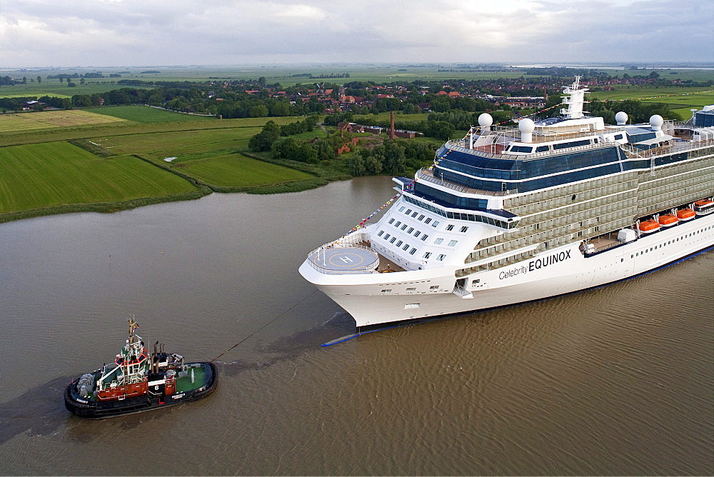 Tug boat navigating the newly launched Celebrity Equinox from the Meyer Werft along the River Ems, Lower Saxony, Germany