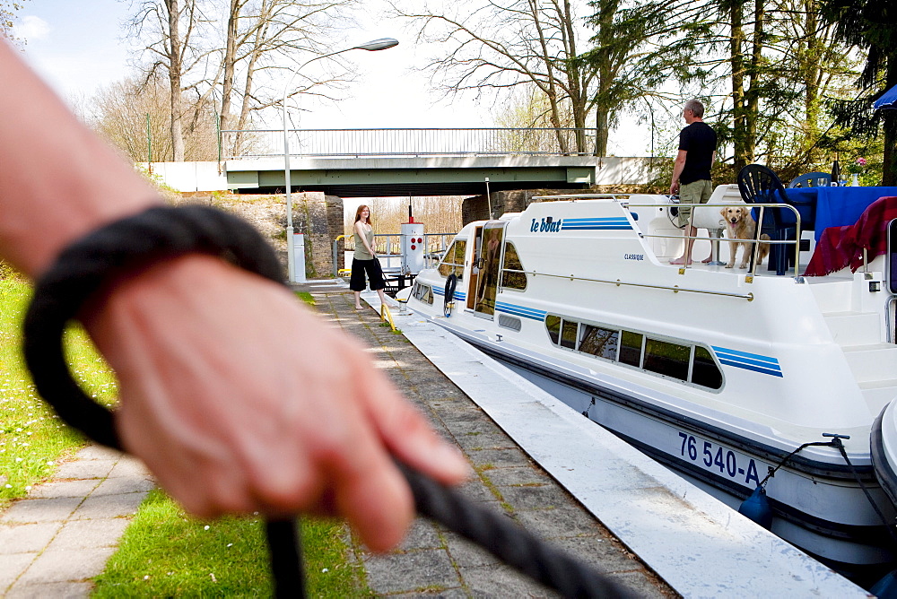 Hand holding a rope to manoeuvre a houseboat through the lock near Zechlinerhuette, North Brandenburg Lake District, Brandenburg, Germany