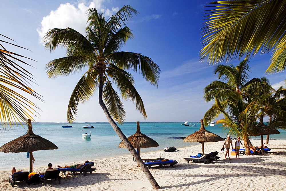 Palm trees and people on the beach of Beachcomber Hotel Paradis &amp;amp; Golf Club, Mauritius, Africa