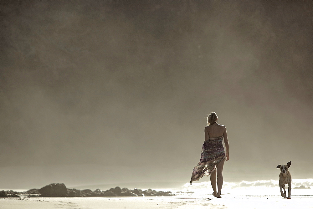 Young woman walking at the beach with a dog, Fuerteventura, Spain