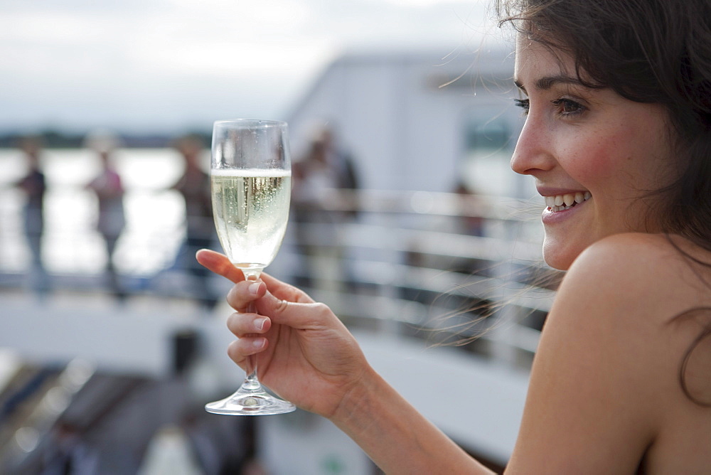 Woman holds champagne glass aboard cruise ship MS Astor (Transocean Kreuzfahrten), MR, Kiel, Schleswig-Holstein, Germany