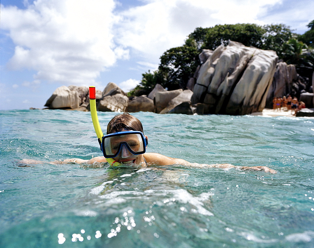 Snorkelling in shallow water over coral reef off tiny Coco Island, La Digue and Inner Islands, Republic of Seychelles, Indian Ocean