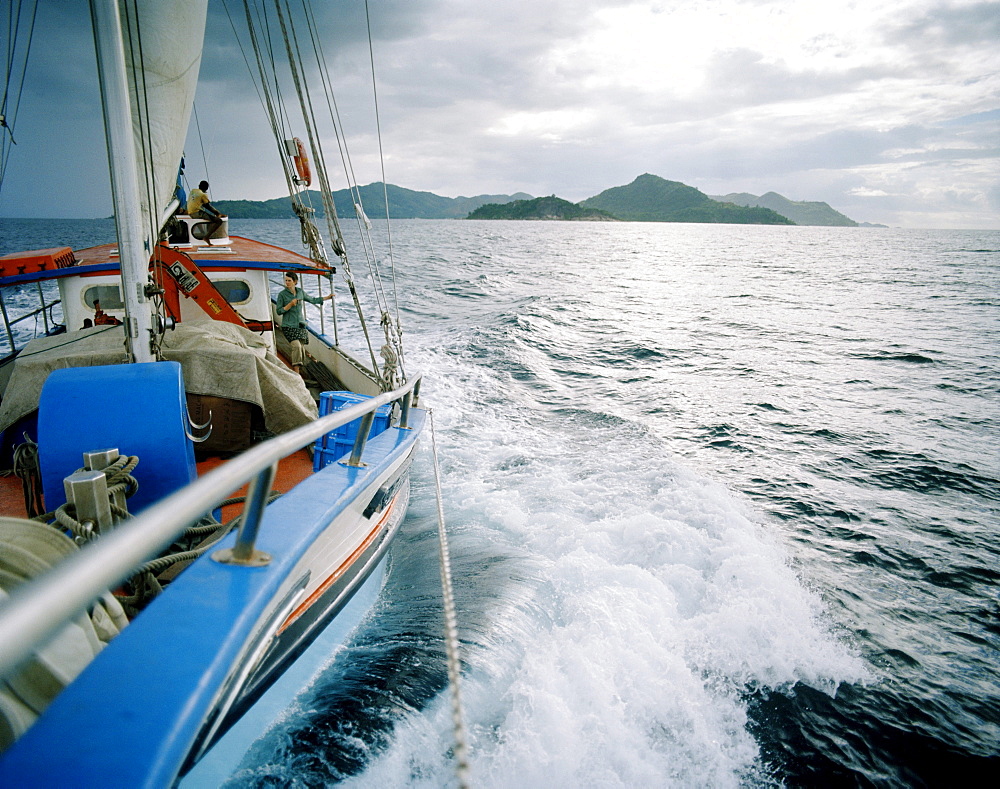 Transport sailer La Belle Praslinoise on its way to La Digue, dark rain clouds over La Digue, La Digue, La Digue and Inner Islands, Republic of Seychelles, Indian Ocean