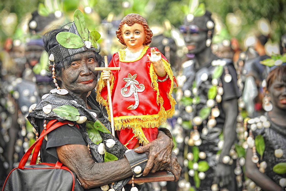 Old woman holding a Santo Nino figur, Ati Atihan festival, Kalibo, Aklan, Panay Island, Visayas, Philippines