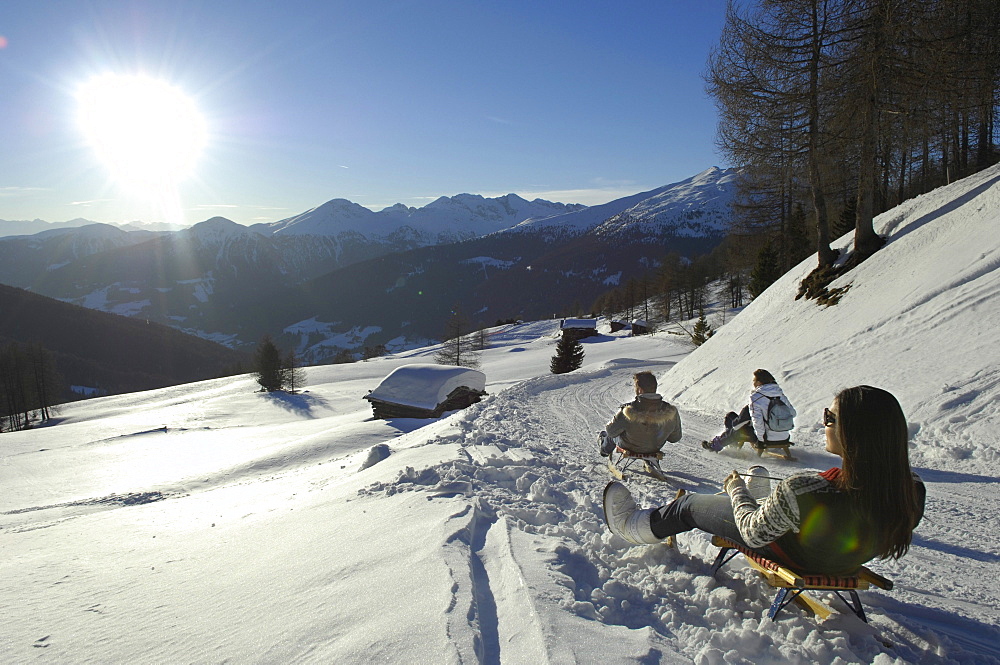 People sledding downhill in snowy mountain scenery, Alto Adige, South Tyrol, Italy, Europe