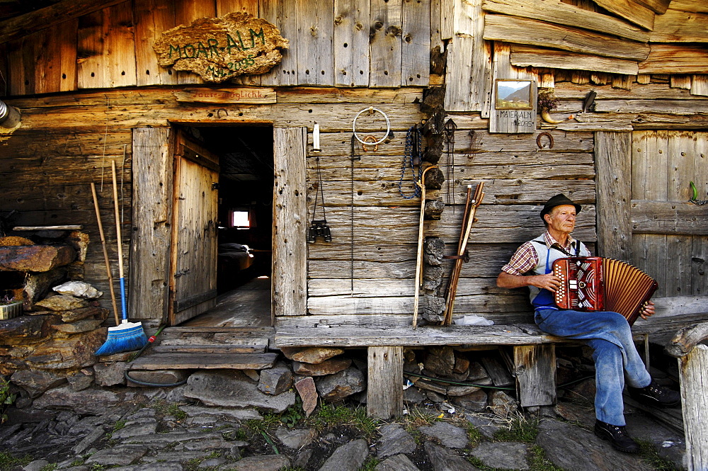 Dairyman playing accordion in front of his house, Schnals Valley, Alto Adige, South Tyrol, Italy