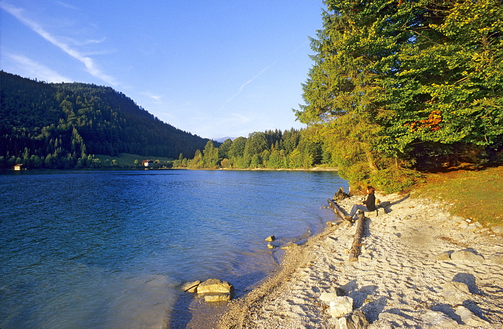 Woman on shore of Walchensee in the light of the evening sun, Walchensee, Bavaria Germany, Europe