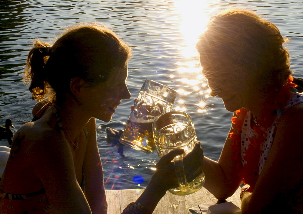 Young women toasting with beer steins, Seehaus Beergarden, English Garden, Munich, Bavaria, Germany