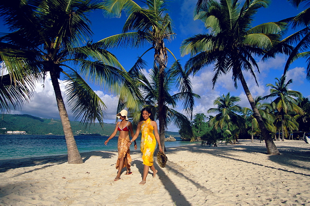 Two women walking along the beach at Cayo Levantado, Bahia de Samana, Dominican Republic, Caribbean