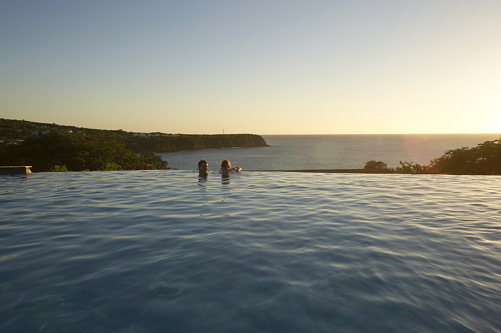 People in the pool of Hotel Restaurant Le Rayon Vert in the light of the evening sun, Deshaies, Basse-Terre, Guadeloupe, Caribbean Sea, America