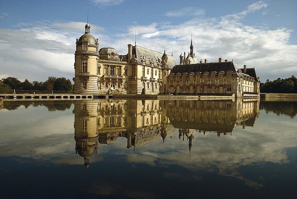 The castle Chateau de Chantilly and reflection in a lake, Ile de France France, Europe