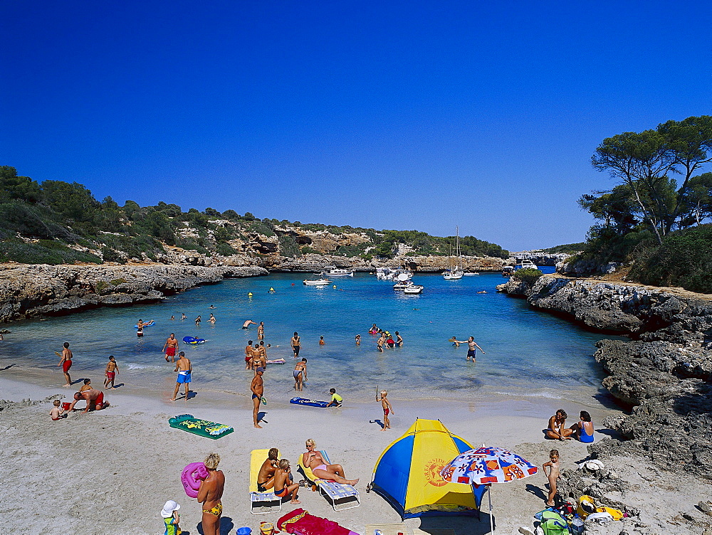 People sunbathing on the beach at Cala de Sanau, near Porto ColÃ›m, Mallorca, Spain