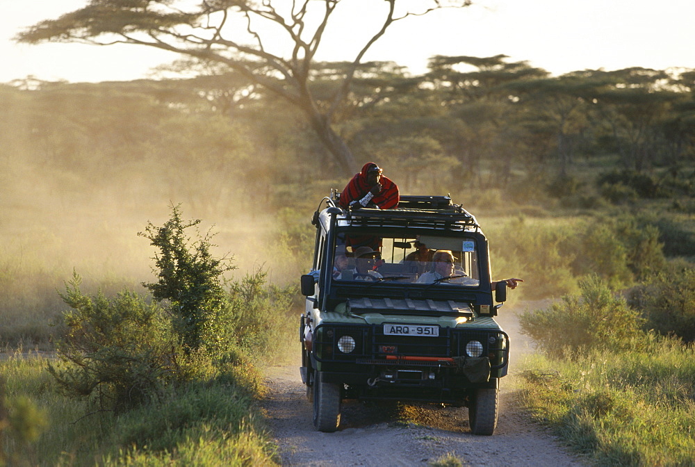 Tourists on a safari with massai tour guide, Serengeti, Tansania, East Africa