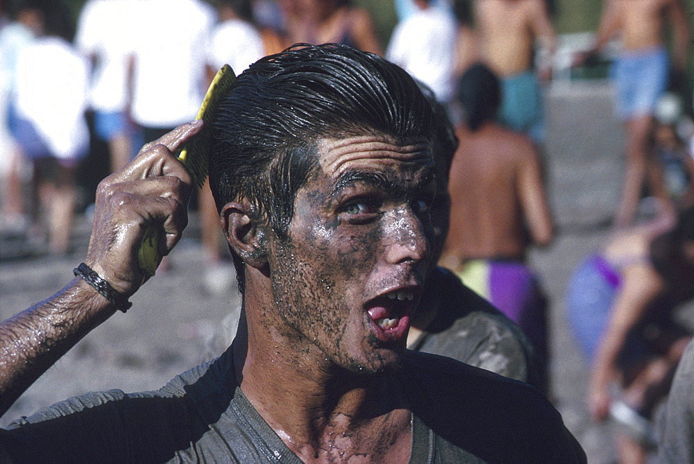 Young man in mud brushing his hair, The Pond Holiday, El Charco, San Nicolas de Tolentino, Gran Canaria, Canary Islands, Spain