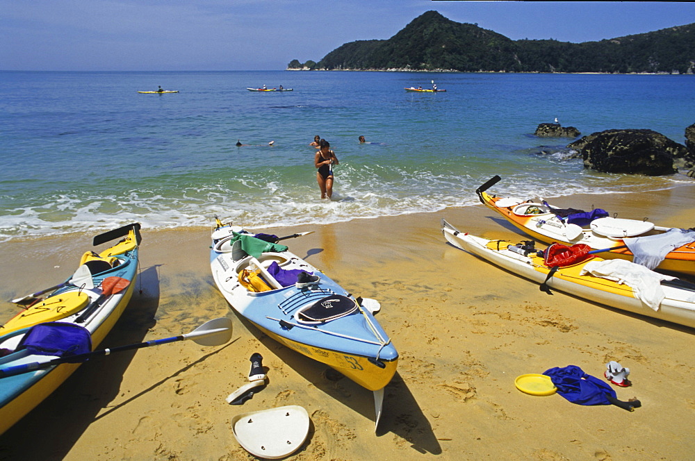 People and kayaks on the beach in the sunlight, Abel Tasman Coast Track, Abel Tasman National Park, New Zealand, Oceania