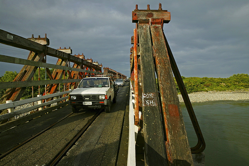 Wooden bridge under clouded sky, traffic and railway sharing the narrow bridge, West Coast, South Island, New Zealand, Oceania