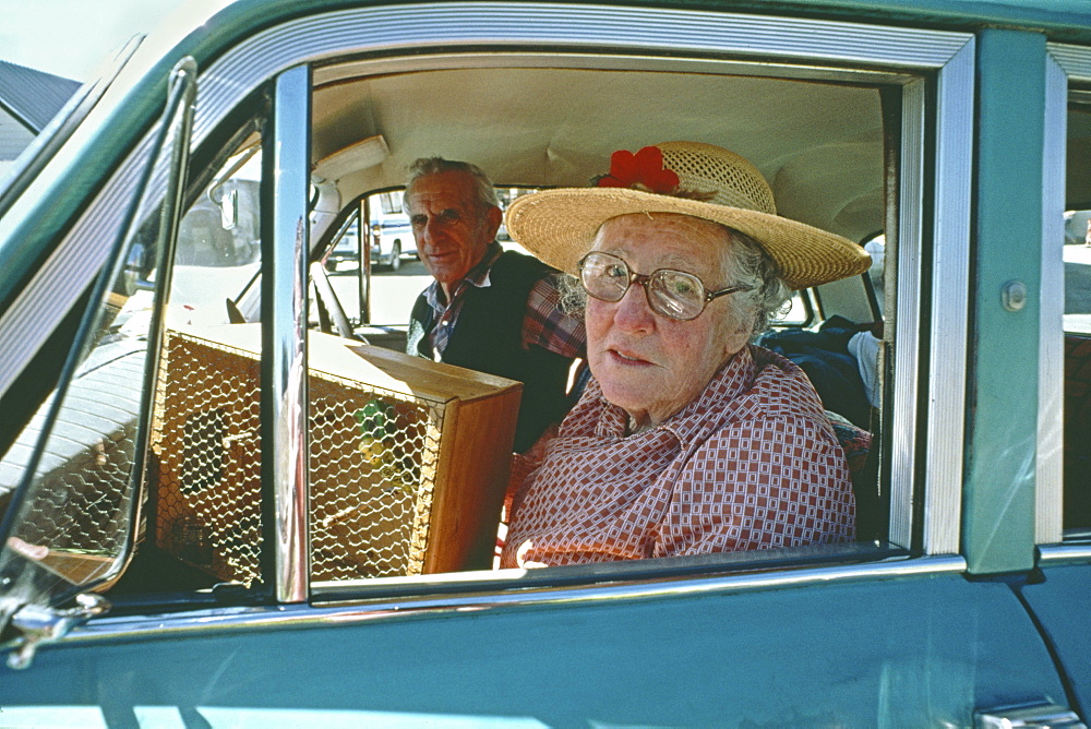 Old couple with budgie in vintage car, South Island, New Zealand