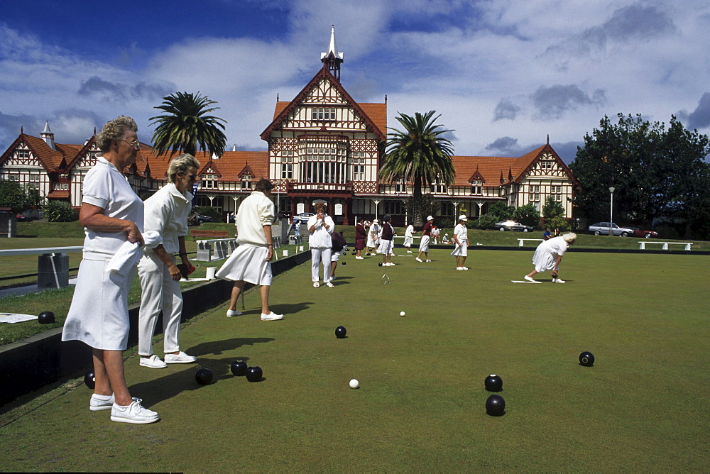 Ladies in white uniforms playing lawn bowls in front of old spa, Rotorua, North Island, New Zealand