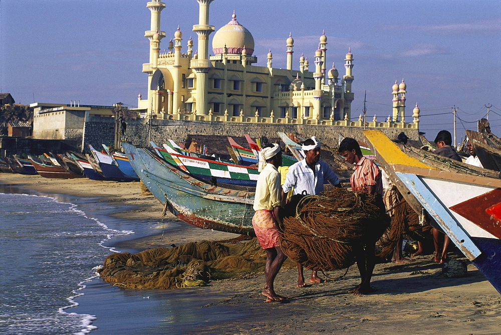 Fishermen and boats on the beach in front of mosque, Kovalam, Kerala, India