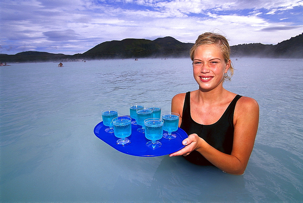 Young woman serving drinks in warm weater lake, Blue Lagoon, Grindavik, Iceland