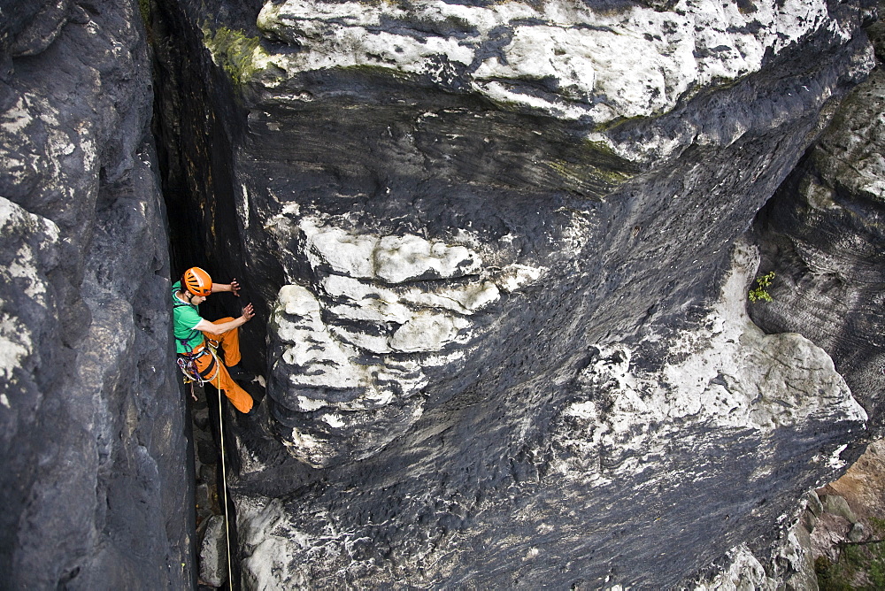 Young man climbing up a rock chimney, Papststein, Elbe Sandstone Mountains, Saxon Switzerland, Saxony, Germany