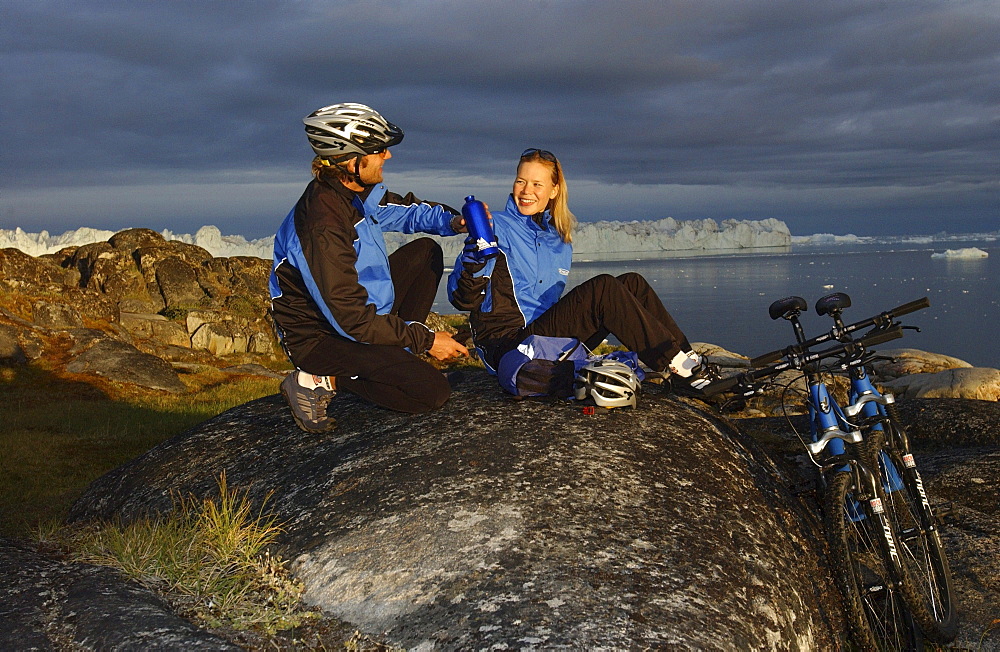 A couple having a break after mountainbiking, Jakobshavn, Ilulissat, Greenland