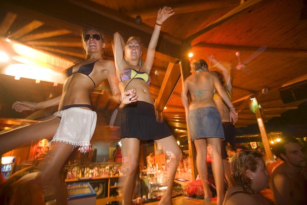 Young girls dancing a table during the full moon party, Tropicana Club, Paradise Beach, Mykonos, Greece