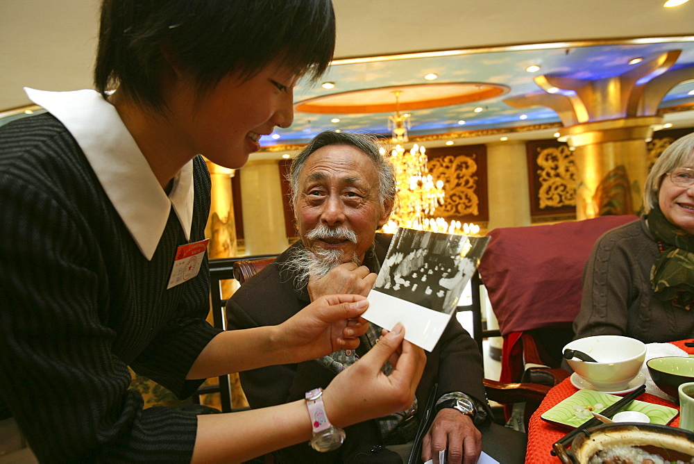 Uebersetzer Zhou Chun, translator Prof. Zhou Chun, shows a waitress a photo of him with Chou En Lai