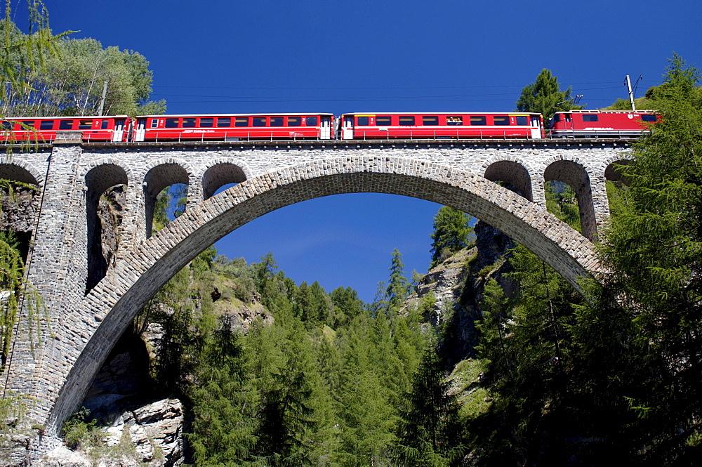 Train crossing a viadukt under blue sky, Guarda, Grisons, Switzerland