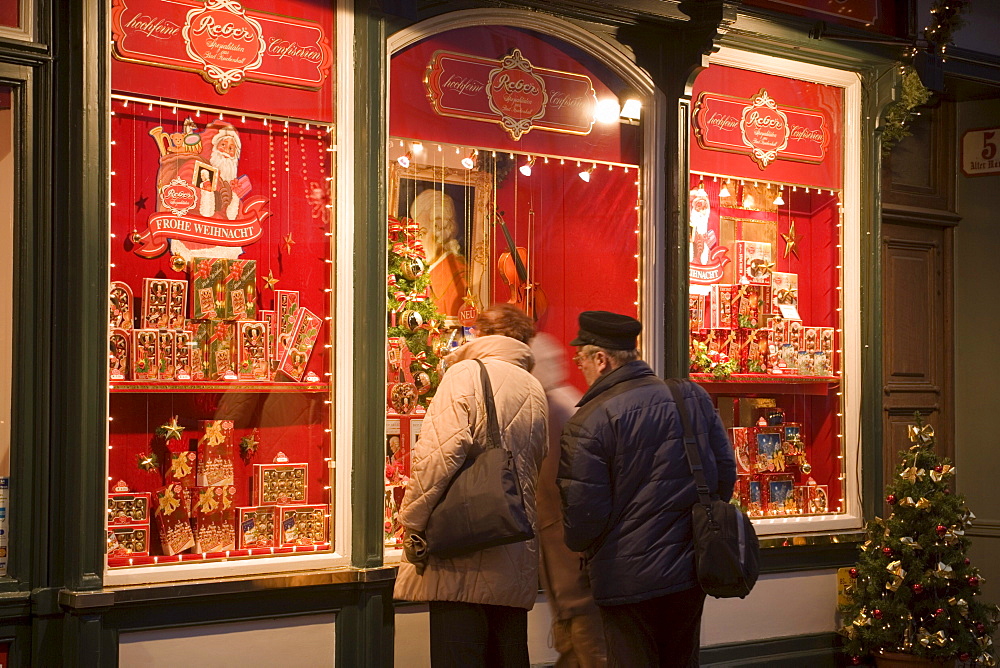 People standing in front of the christmassy decorated shop window of Reber, a shop, where you can buy Mozartkugeln, Old Market, Salzburg, Salzburg, Austria