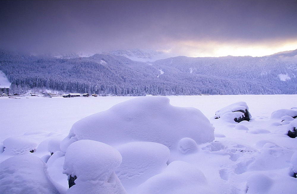 Europe, Germany, Bavaria, near Grainau, snow coverd stones on the frozen up Eibsee with Bavarian Alps