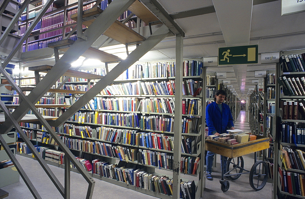 Europe, Germany, Bavaria, Munich, Bavarian State Library, library assistant with a book mobile in a book stack