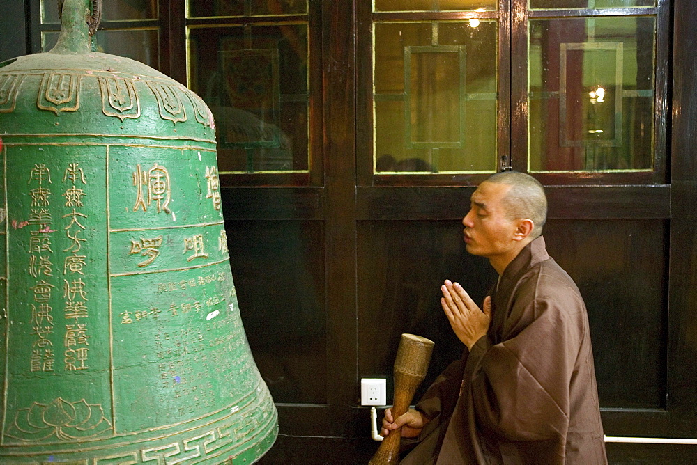 Monk in prayer, meditation, bronze bell, Wannian Monastery and Temple, China