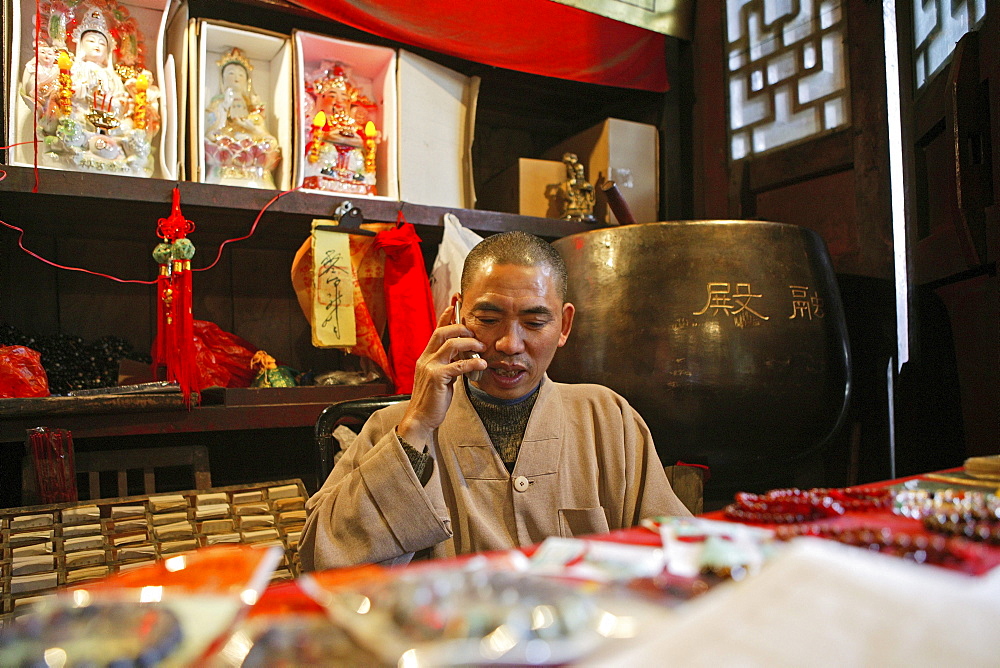 Monk with mobile phone at the entrance of temple, Zhu Rong Feng, Heng Shan South, Hunan province, China, Asia