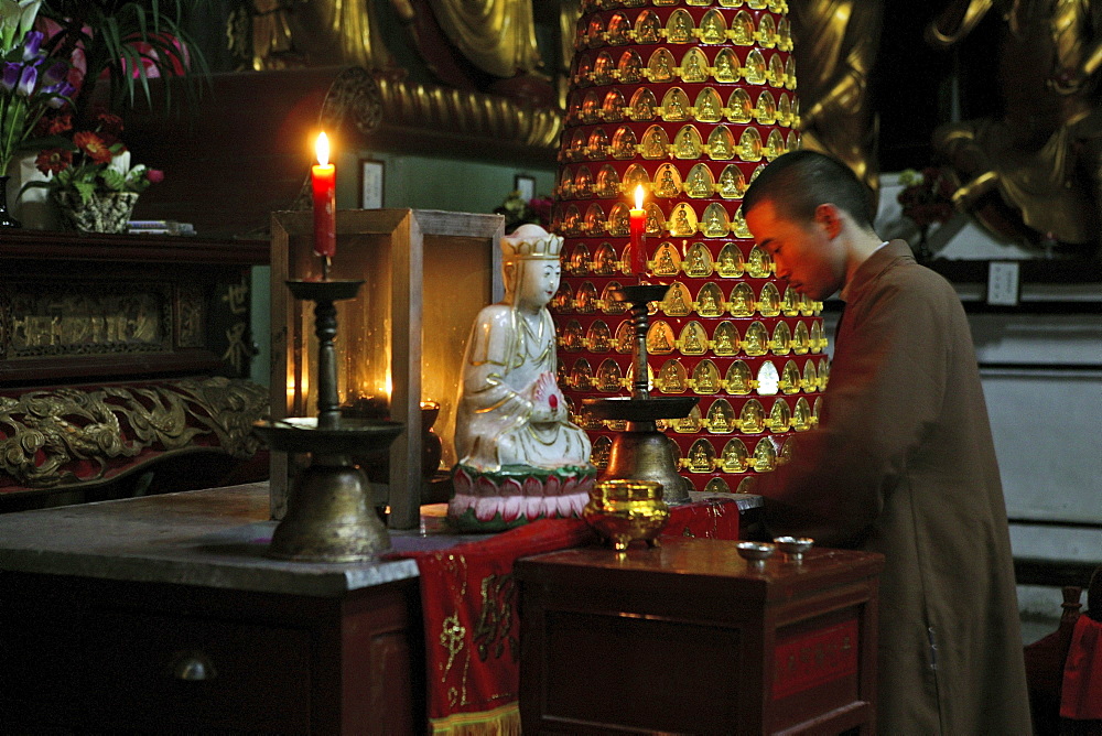 A monk kneeling in front of white Jade Buddha, Sangchan Monastery, Jiuhuashan, Anhui province, China, Asia