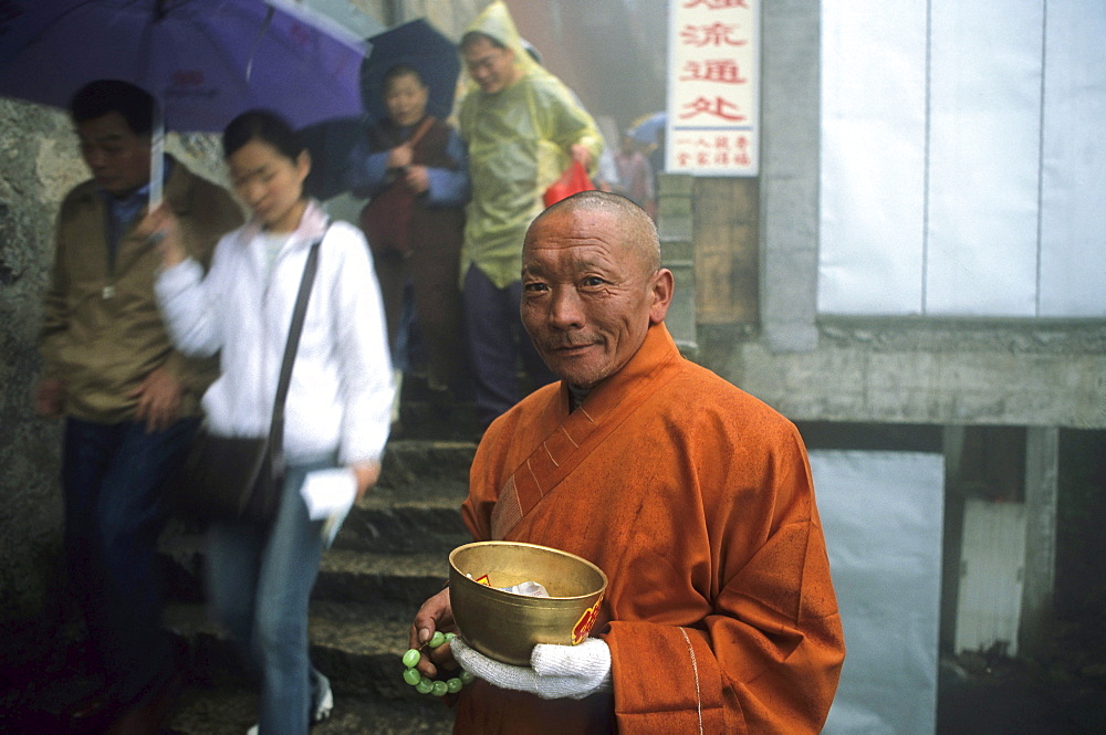 A mendicant and tourists in front of Longevity monastery, Jiuhua Shan, Anhui province, China, Asia