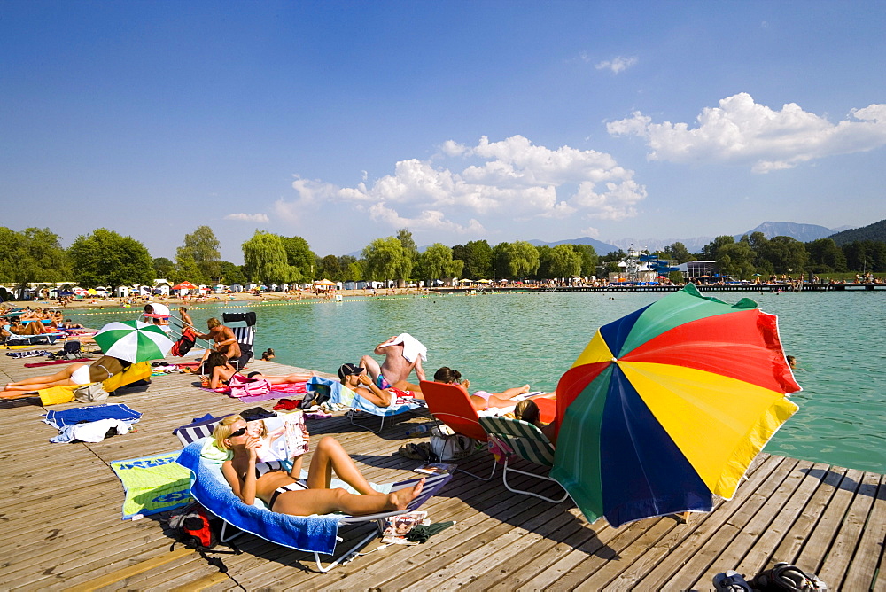 Young people sunbathing on landing stage at Strandbad Klagenfurt, Lake Woerthersee (biggest lake of Carinthia), Klagenfurt, Carinthia, Austria