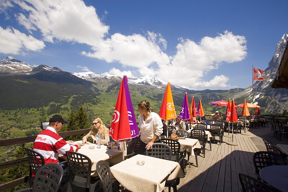 People on sun terrace of the mountain restaurant Pfingstegg, Schreckhorn (4078 m) and Eiger (3970 m) in background, Grindelwald, Bernese Oberland (highlands), Canton of Bern, Switzerland