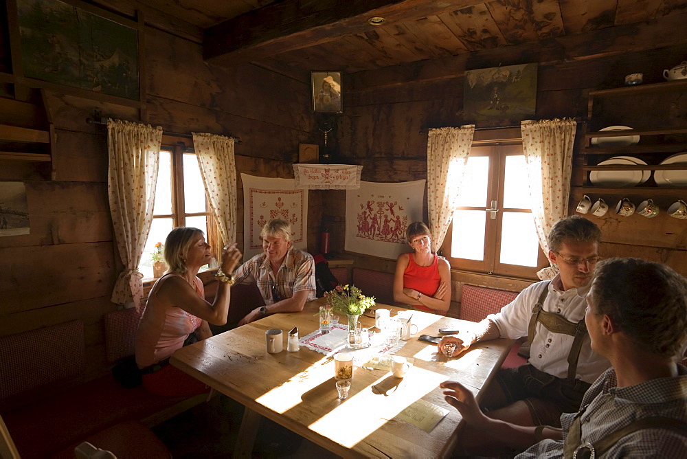 Group of people sitting in the Karseggalm Hut (1603 m, one of the oldest mountain hut in the valley), Grossarl Valley, Salzburg, Austria