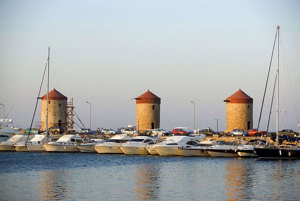 View over Mandraki harbour (translated literally: fold) with anchoring ships to windmills on mole, Rhodes Town, Rhodes, Greece