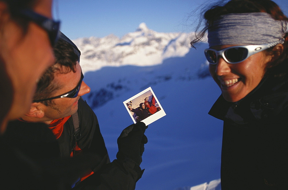 Man showing photograph to two friends, Snowshoeing, Mountain sports, Winter, Nebelhorn, Allgaeu, Bavaria, Germany