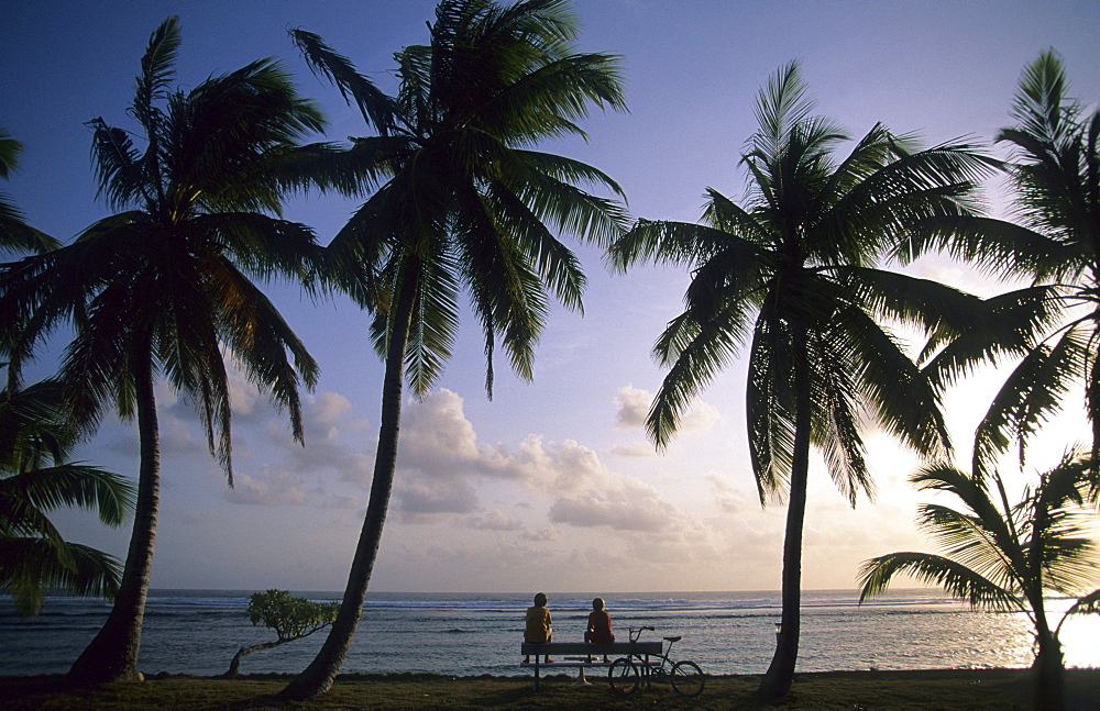 Two cyclists having a rest on a park bench on West Island, Australian