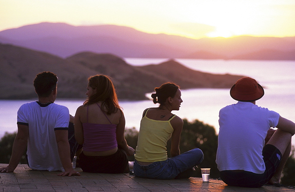 Four young people, couples enjoying the sunset from One Tree Hill on Hamilton Island, Whitsunday Islands, Great Barrier Reef, Australia