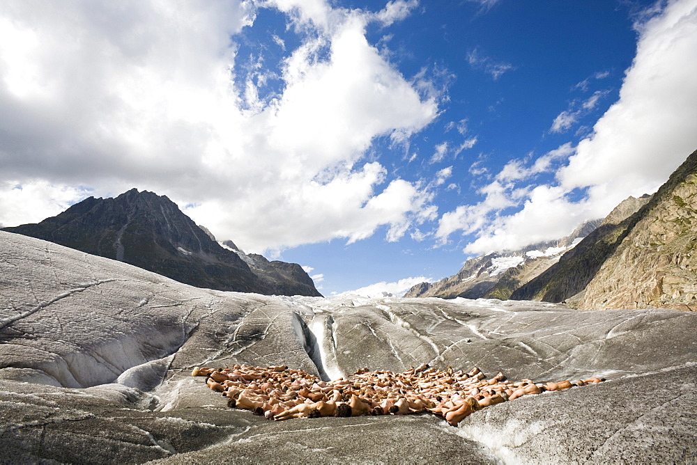 A group of naked people lying on the ice in front of an ice crevasse, around 600 people are posing for Spencer Tunick and Greenpeace on the Aletsch Glacier to protest about climate change, Aletsch Glacier, Valais, Switzerland